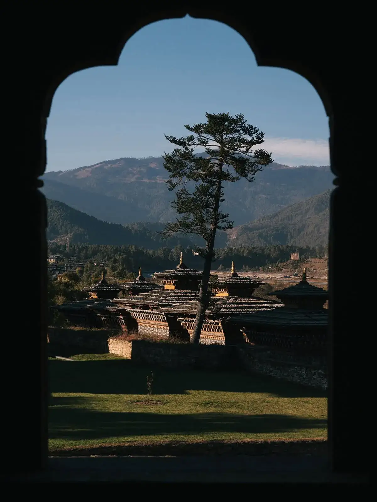 A carved wooden doorway opening onto a green valley